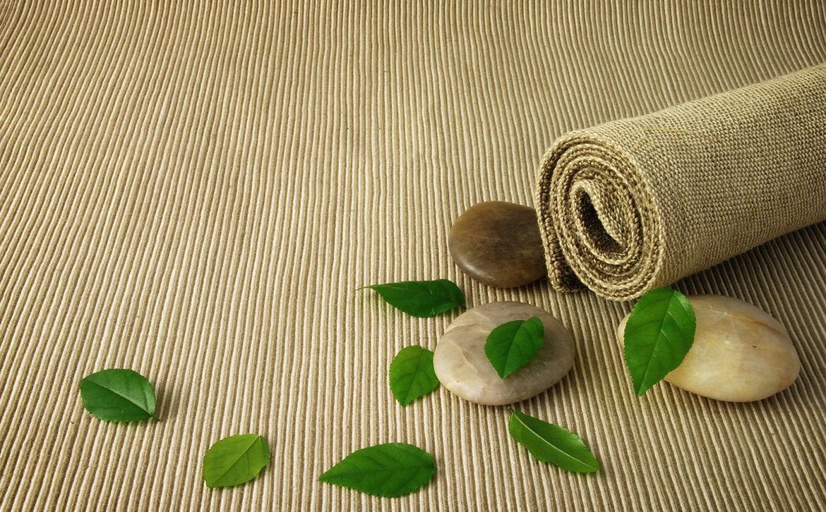Smooth stones and fresh green leaves on a woven mat